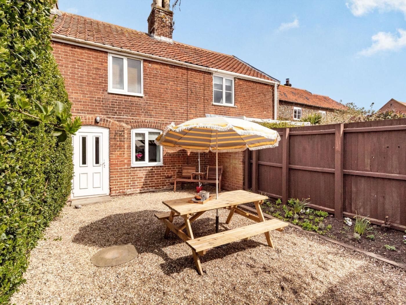A brick house with a patio, a wooden table, and an umbrella.