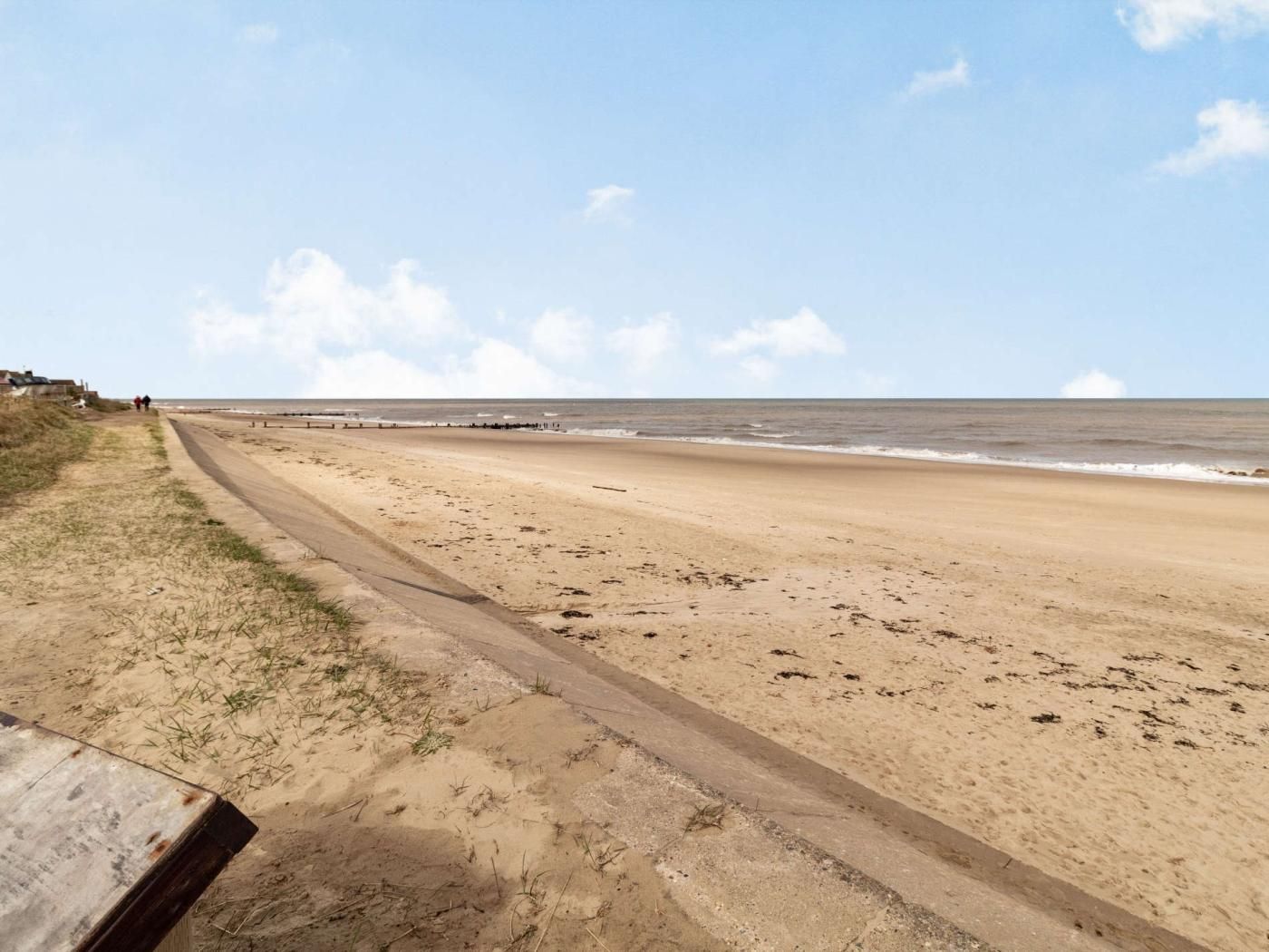 Une plage de sable avec une promenade dallée et une vue sur la mer.