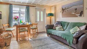 Een gezellige woonkamer met een eethoek, een groene bank en een schilderij aan de muur.
