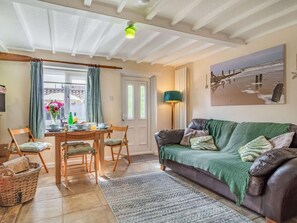 Ein gemütliches Wohnzimmer mit Essbereich, einem grünen Sofa und einem Gemälde an der Wand.