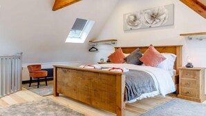 Quarto com cama de madeira, claraboia, radiador, cadeira e mesa de cabeceira.