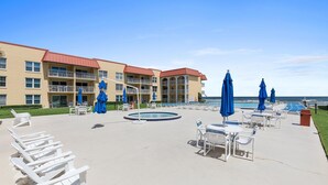 Ein Hotelpoolbereich mit Liegestühlen und Sonnenschirmen, ein Schwimmbecken und ein Gebäude mit Balkonen.