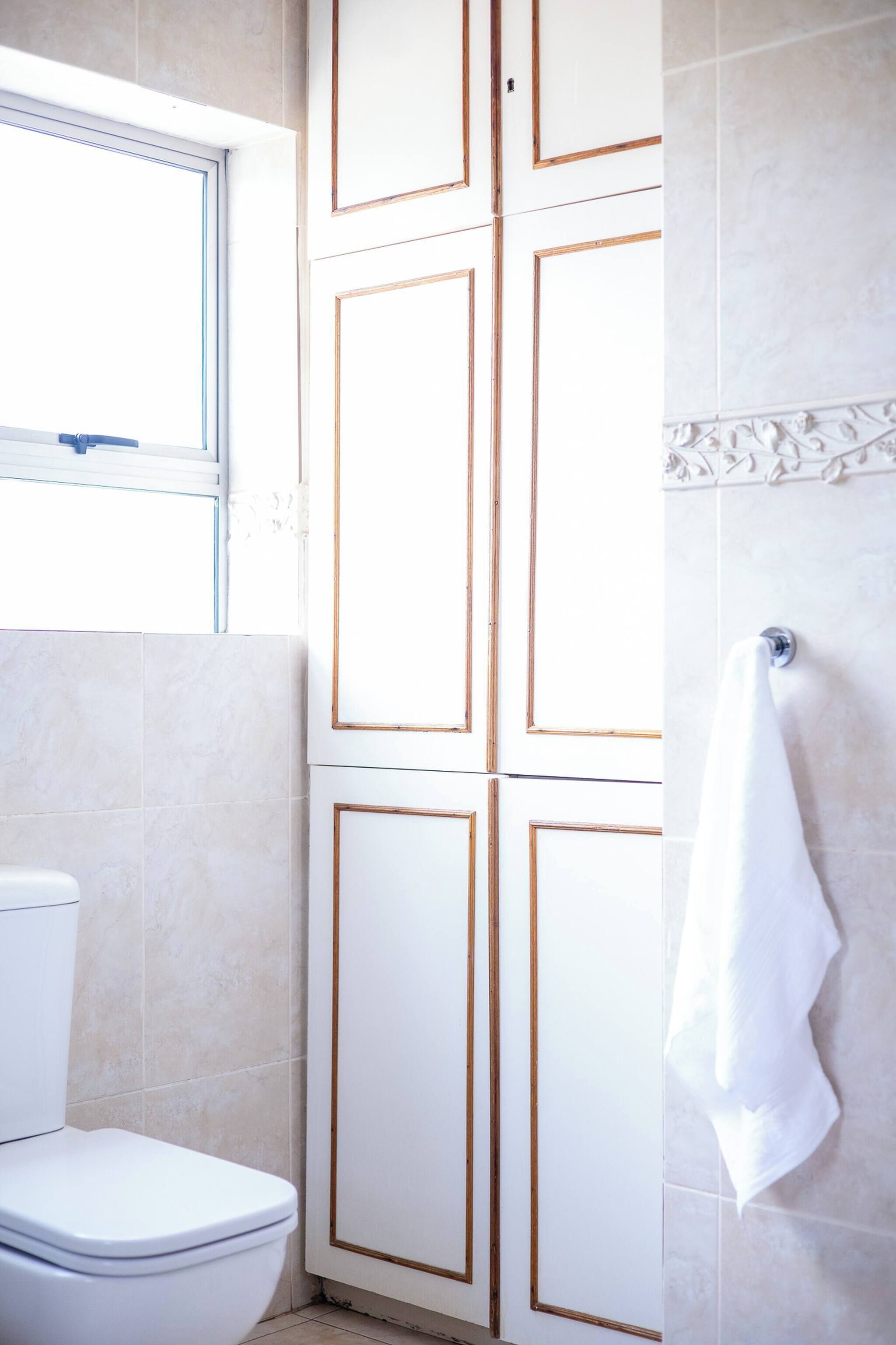 Ein Badezimmer mit Toilette, einem Handtuch an der Wand und einem Fenster.