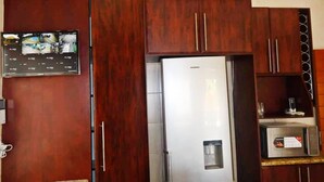 Una cocina con refrigerador empotrado, armarios de madera y una pequeña encimera con microondas.