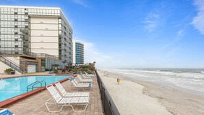 A hotel pool area with lounge chairs and a view of the beach. - Oceanside Inn 605 (Daytona Beach Shores)