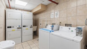 A laundry room with stacked washers and dryers, a sink, and a water heater. - Oceanside Inn 605 (Daytona Beach Shores)