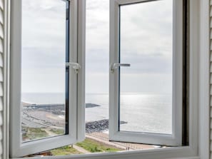 Una ventana con vistas a la costa, que incluye una playa y afloramientos rocosos.