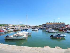 A marina with various boats docked, a large building in the background, and a clear sky.