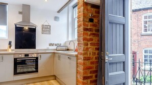 A modern kitchen with a brick column, a built-in oven, and a large window. - 1 Bed in Matlock (oc-86416) (Wirksworth)