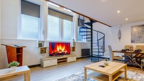 A modern living room with a fireplace, a spiral staircase, and a dining area. - 1 Bed in Matlock (oc-86416) (Wirksworth)