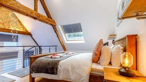 A bedroom with a sloped ceiling, a bed with pillows, a nightstand with a lamp, and a window with blinds. - 1 Bed in Matlock (oc-86416) (Wirksworth)