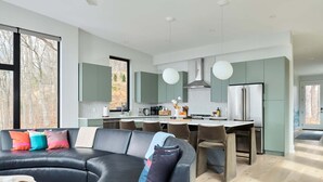 Una cocina moderna con una isla central, taburetes de bar y una mesa de comedor.