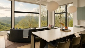 Una cocina moderna con una isla grande, sillas de comedor y vistas a montañas a través de amplios ventanales.
