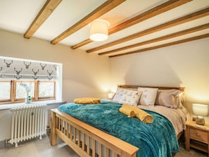 A bedroom with a wooden bed, a window with a curtain, a bedside table with a lamp, and a radiator. - 3 Bed in Norwich (oc-86387) (Sloley)