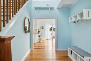 Ein Korridor mit einer Holztreppe, einer weißen Bank und einem Spiegel an der Wand.