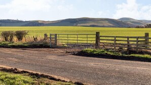 A rural road with a wooden gate leading to a green field. - 2 Bed in Mindrum (oc-86637) (Carham)