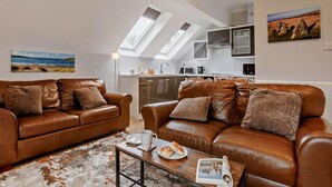 Ein modernes Loft-Apartment mit Küche, zwei Ledersofas, einem Couchtisch und einem großen Fenster mit Oberlichtern.