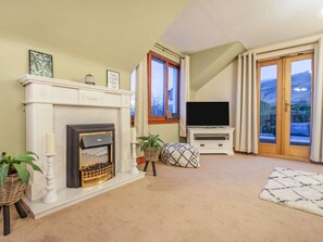 A living room with a fireplace, television, and a view of the outdoors.