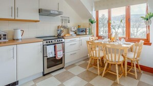 Eine Küche mit Herd, Backofen und Esstisch mit Stühlen.