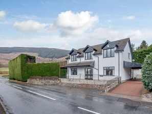 A two-story house with a stone foundation, a paved driveway, and a view of the surrounding landscape. - 5 Bed in Aberfeldy (oc-86687) (Fearnan)