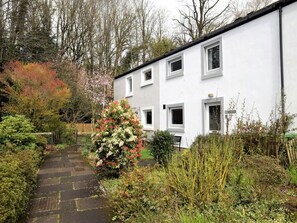 A white building with multiple windows, a paved pathway, and surrounding greenery. - 2 Bed in Keswick (oc-87092) (Keswick)