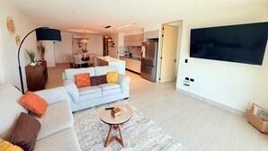 Een moderne woonkamer met een bank, salontafel en een aan de muur bevestigde televisie.