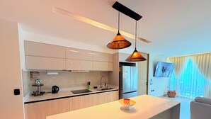 Een moderne keuken met een centraal eiland, een inbouwoven en een groot raam met gordijnen.