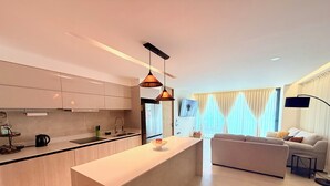 Een moderne keuken met een centraal eiland, een zithoek met een bank en een woonkamer met televisie.