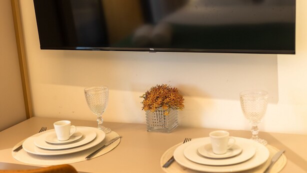 A dining table set with plates, cutlery, and a vase with dried flowers. - Restinga Foot in the Sand by Carpediem (João Pessoa)