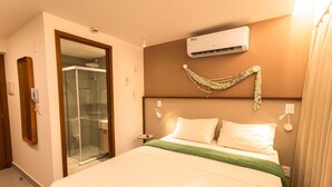 A hotel room with a bed, a glass shower enclosure, an air conditioning unit, and a wall-mounted decorative item. - Restinga Foot in the Sand by Carpediem (João Pessoa)