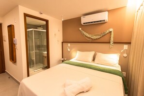 Ein Hotelzimmer mit Bett, einer Glasdusche, einer Klimaanlage und einem Wanddekor.