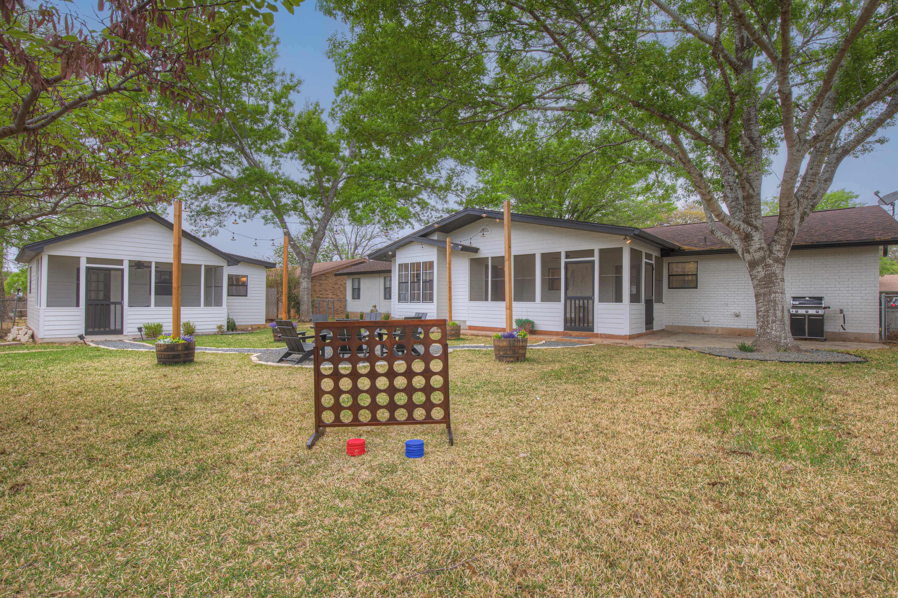 A residential area with two houses, a wooden fence, and a tree.
