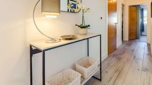 En gang med et konsolbord, en lampe, en orkidé i potte, fletkurve og et spejl.