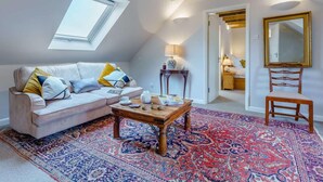 A loft-style room with a sloped ceiling, a skylight, a sofa, a coffee table, a rug, a chair, a bedside table, a lamp, and a mirror. - 1 Bed in Cranbrook (oc-87119) (Benenden)