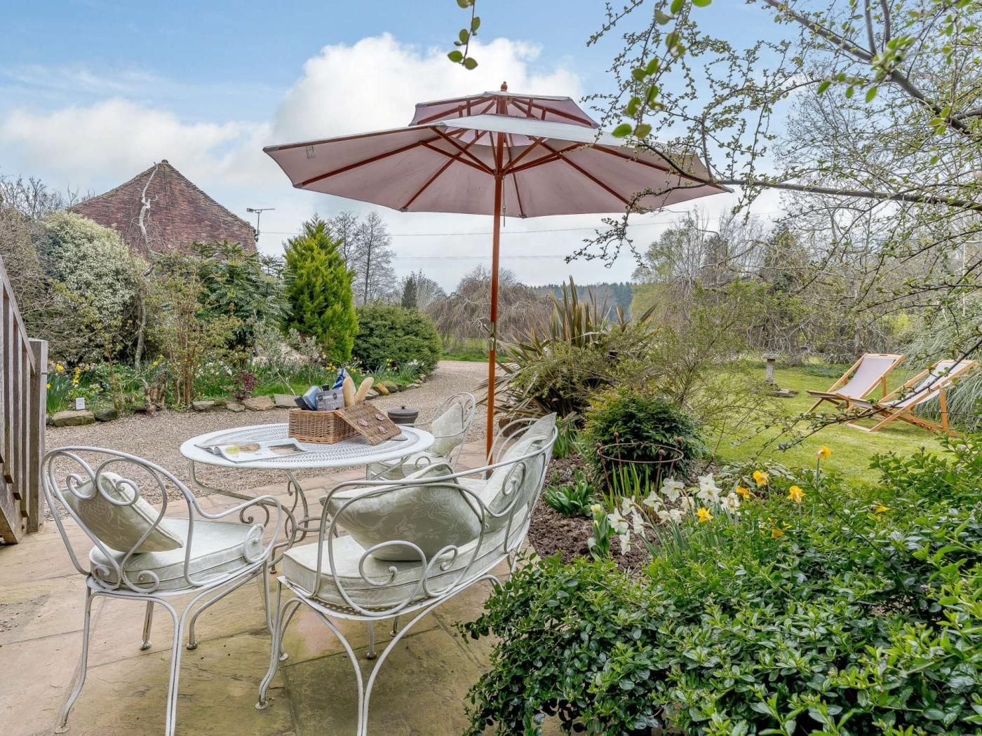 An outdoor patio with a round table, two chairs, a large umbrella, and a view of a mountain.
