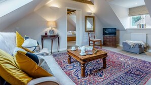 A cozy loft bedroom with a sloped ceiling, a large window, a bed, a TV, and a small table with a lamp. - 1 Bed in Cranbrook (oc-87119) (Benenden)