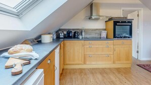 A kitchen with a skylight, wooden cabinets, a built-in oven, and a countertop with a loaf of bread and a cutting board. - 1 Bed in Cranbrook (oc-87119) (Benenden)