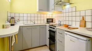 Una cucina compatta con lavello, fornelli, microonde ed elettrodomestici.