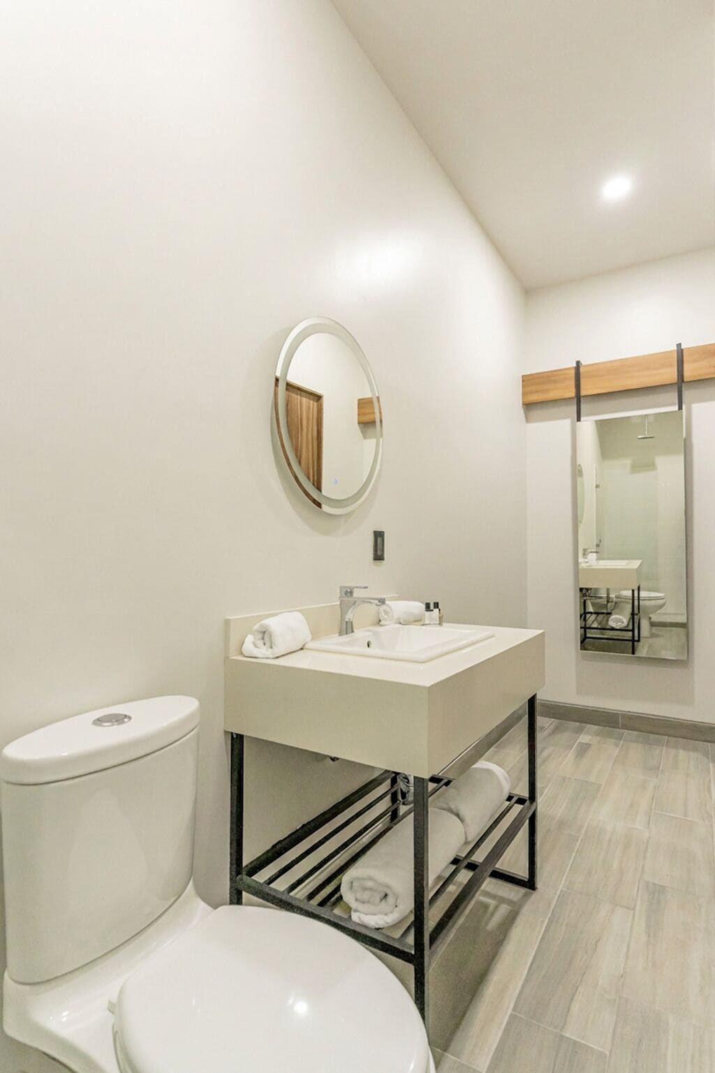 Un baño moderno con inodoro, lavamanos y espejo.