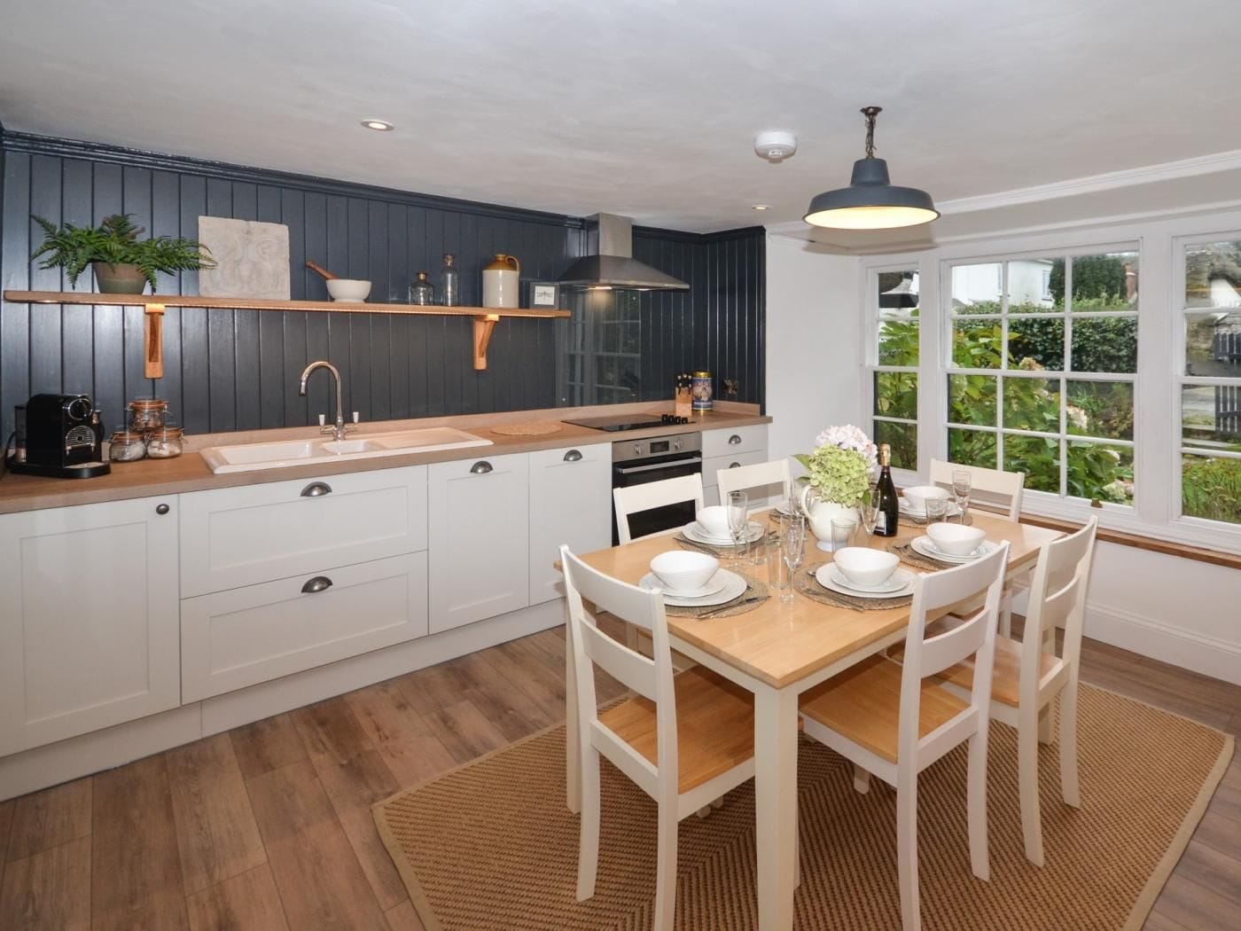 A modern kitchen with white cabinets, a wooden countertop, and a dining area with a table set for four.