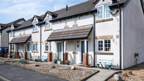 A row of white terraced houses with pitched roofs, front doors, and small front gardens. - 2 Bed in Seahouses (oc-87389) (Seahouses)