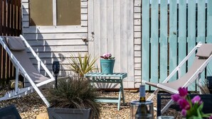 A patio with two lounge chairs, a small table, and a potted plant. - 2 Bed in Seahouses (oc-87389) (Seahouses)
