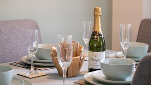A table set for dining with a bottle of Barigny Brut Blanc de Blanc, clear glasses, and wooden cutlery. - 2 Bed in Seahouses (oc-87389) (Seahouses)