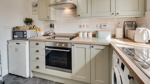 A compact kitchen with a built-in oven, a microwave, and a toaster. - 2 Bed in Seahouses (oc-87389) (Seahouses)