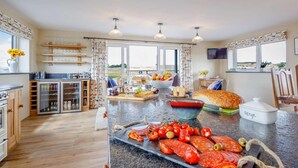 Una cocina amplia con una isla central, un comedor con vistas y un salón con televisión.