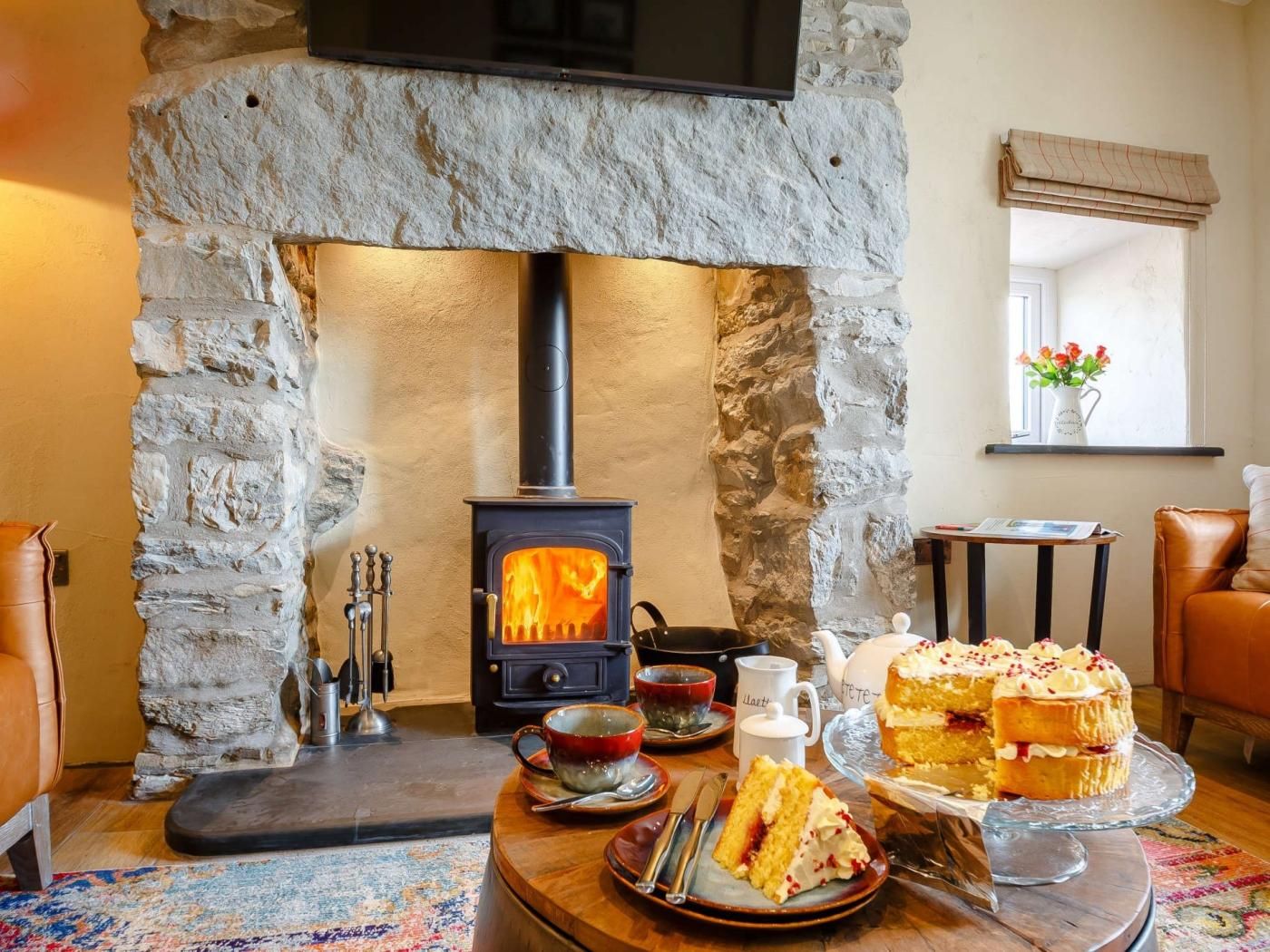 A cozy room with a stone fireplace, a table with a cake, and a leather sofa.