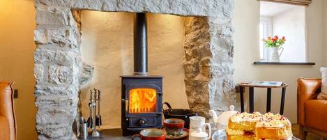 A cozy room with a stone fireplace, a table with a cake, and a leather sofa.