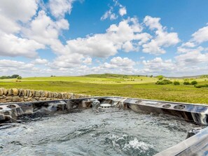 Boblebad med en stenvæg i forgrunden og et grønt landskab i baggrunden.