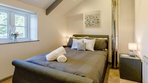 Une chambre à coucher avec un lit, une fenêtre décorée de fleurs, un tableau et une table de chevet.