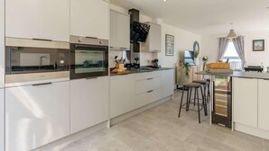 Une cuisine moderne dotée d’appareils électroménagers intégrés, un coin repas avec des tabourets et une vue sur l’extérieur.